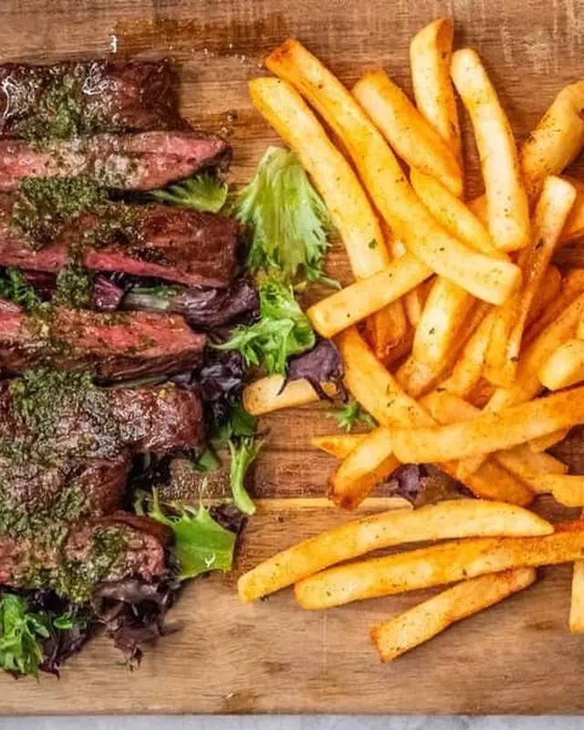 Steak and fries plated on a wooden board