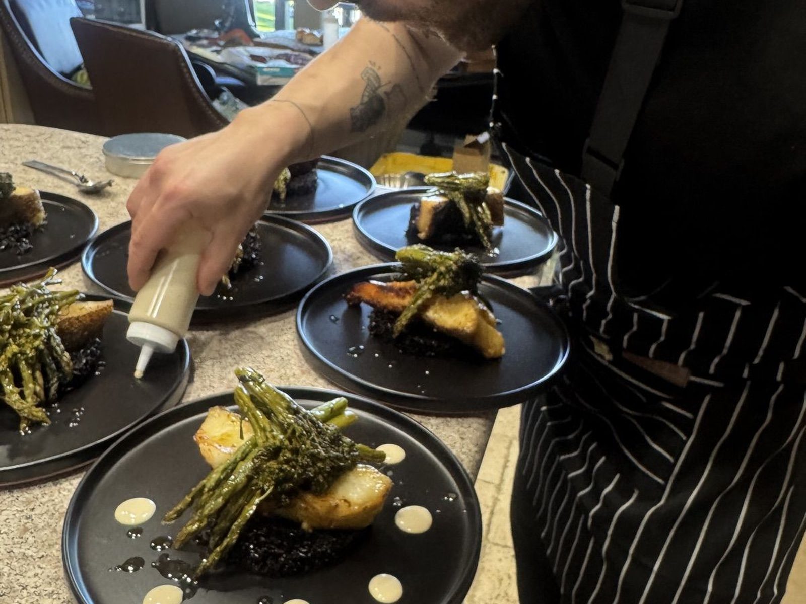 Chef Fikret plating sauce dots on identical fish courses