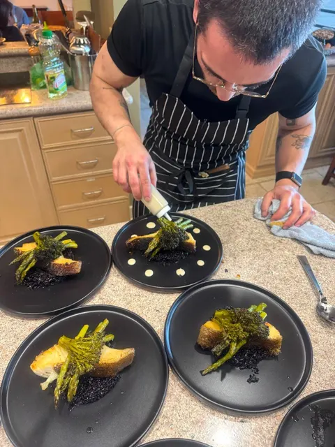 Chef plating sauce on seared fish courses