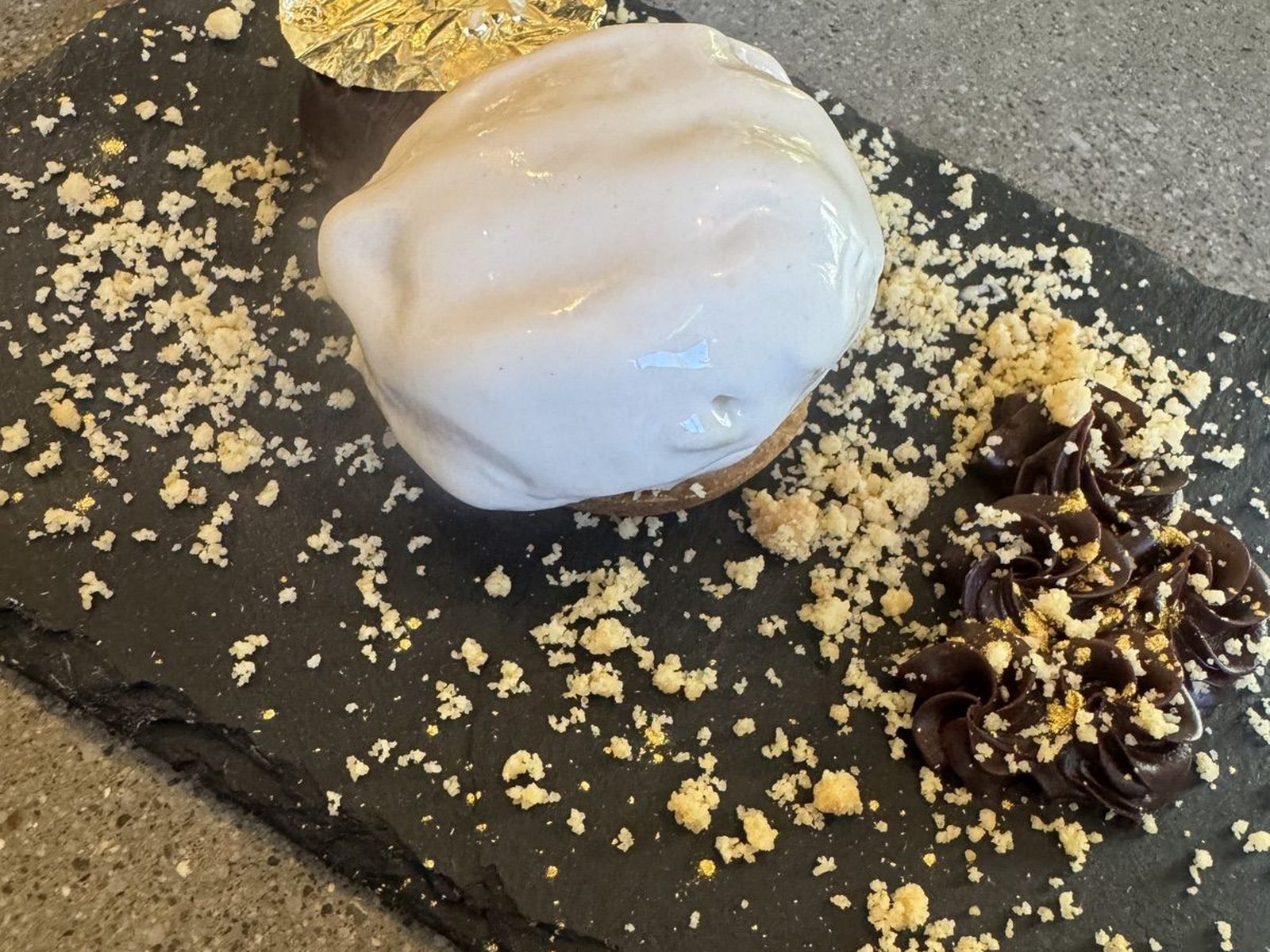 White glazed dessert sphere with gold leaf and chocolate swirl on slate