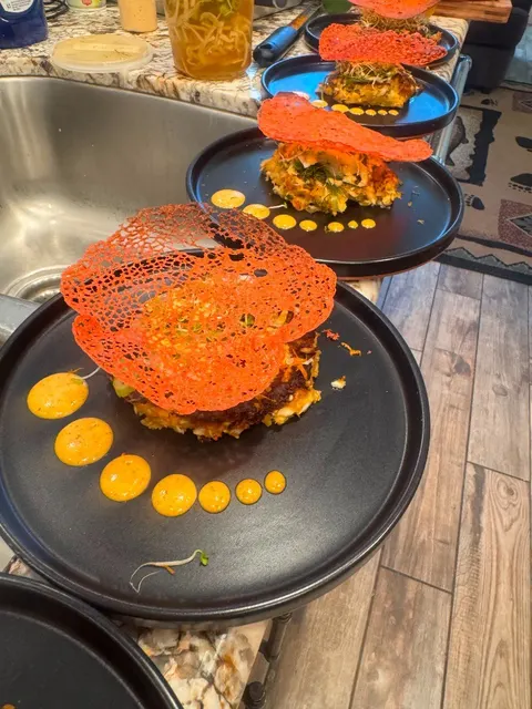 Plated savory stacks with coral tuile and orange sauce dots